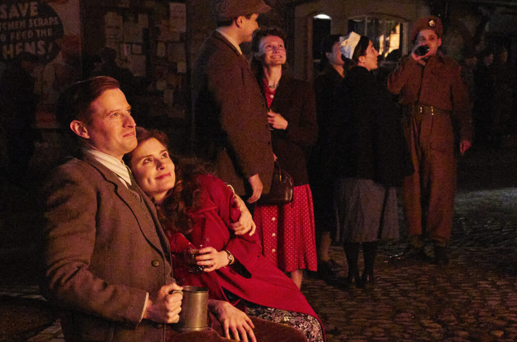 James and Helen sitting on a bench outside looking up at the night sky.