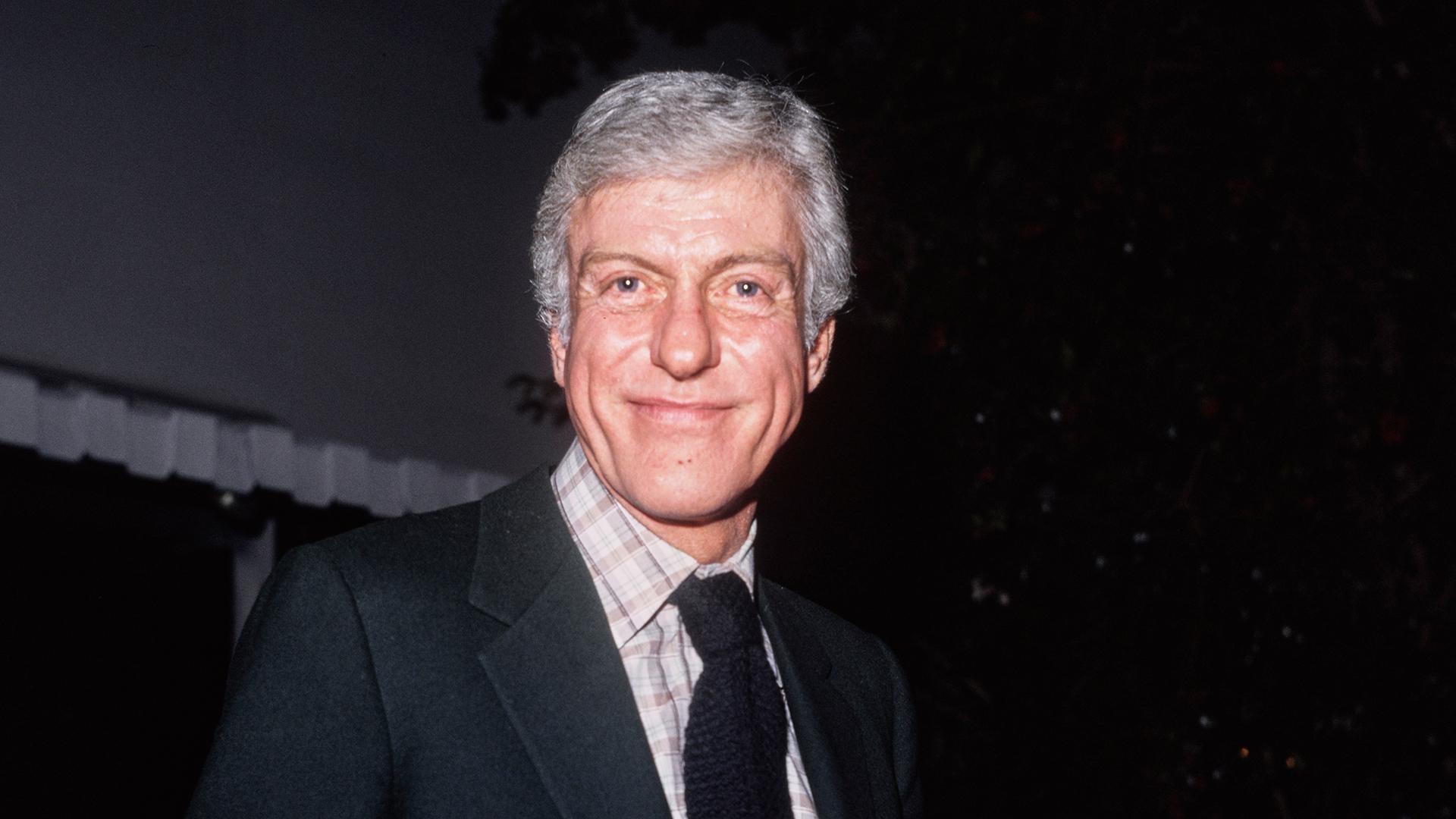 Dick Van Dyke wearing a gray blazer and white and gray plaid shirt and Black tie.