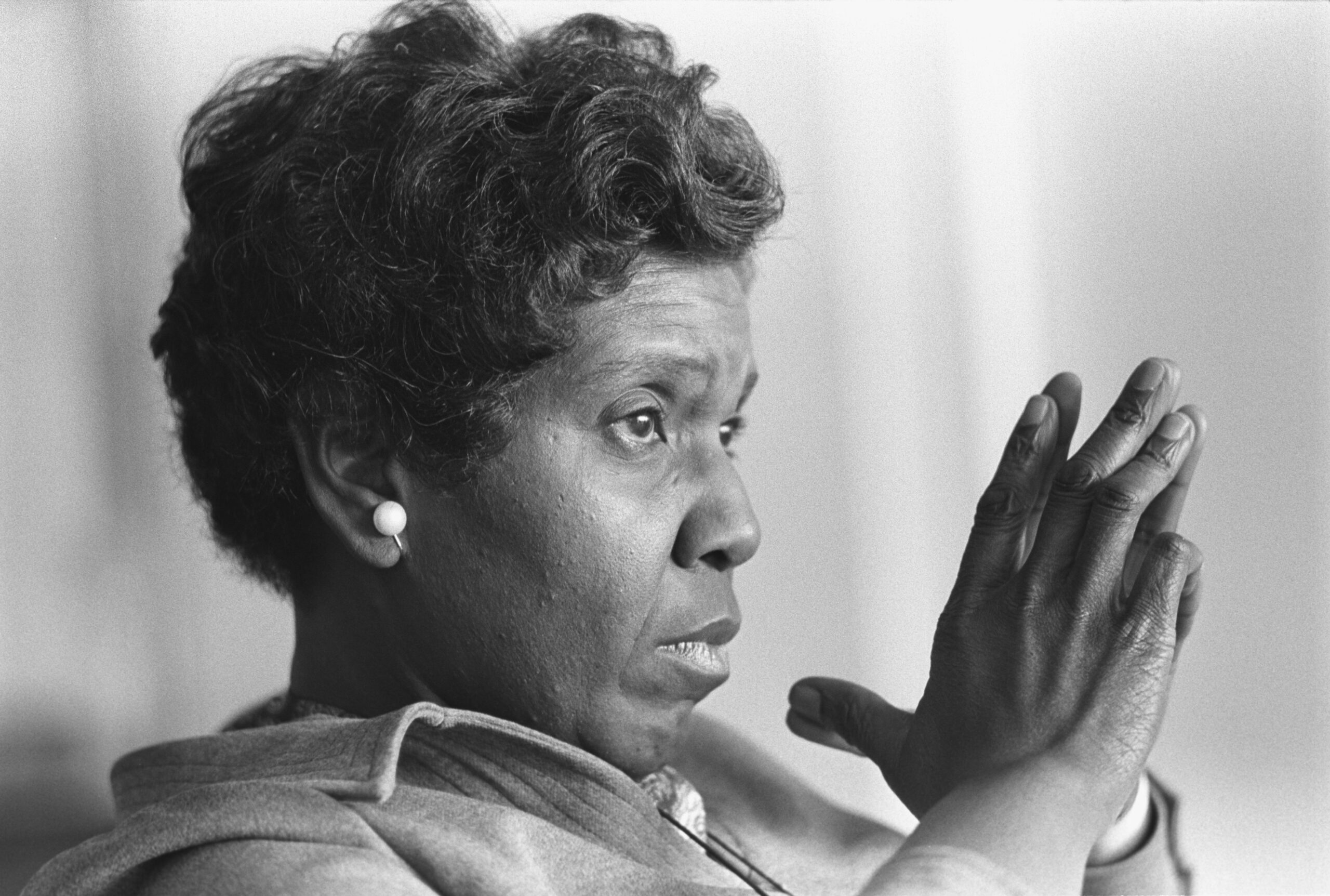 A close up blacka nd white shot of Barbara Jordan. She has her hangs together in front of her face looking pensive.
