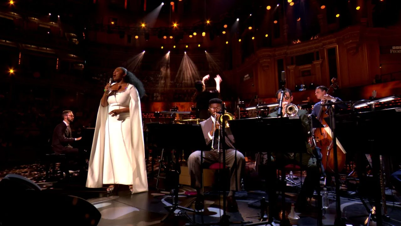 A Black woman in a white dress singing on stage.