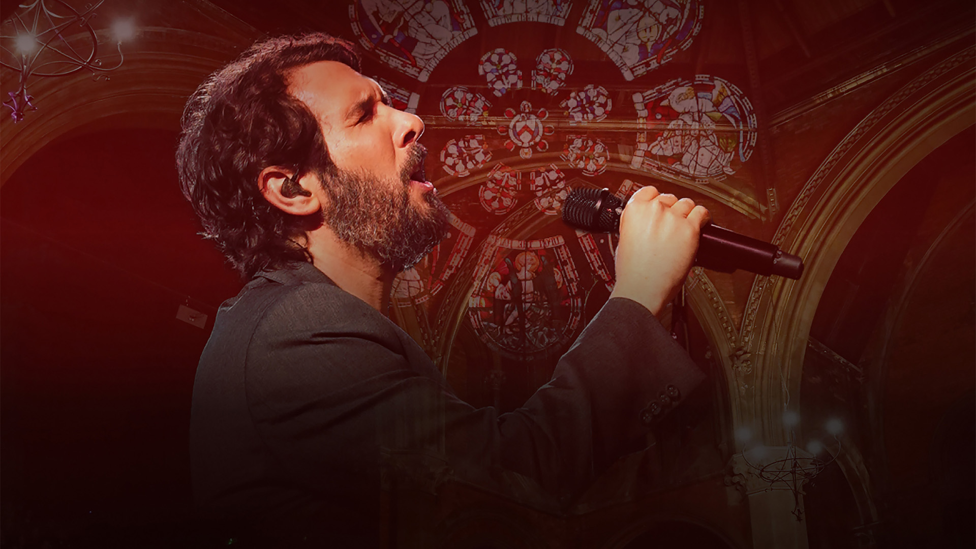 Josh Groban in a black suite on stage singing