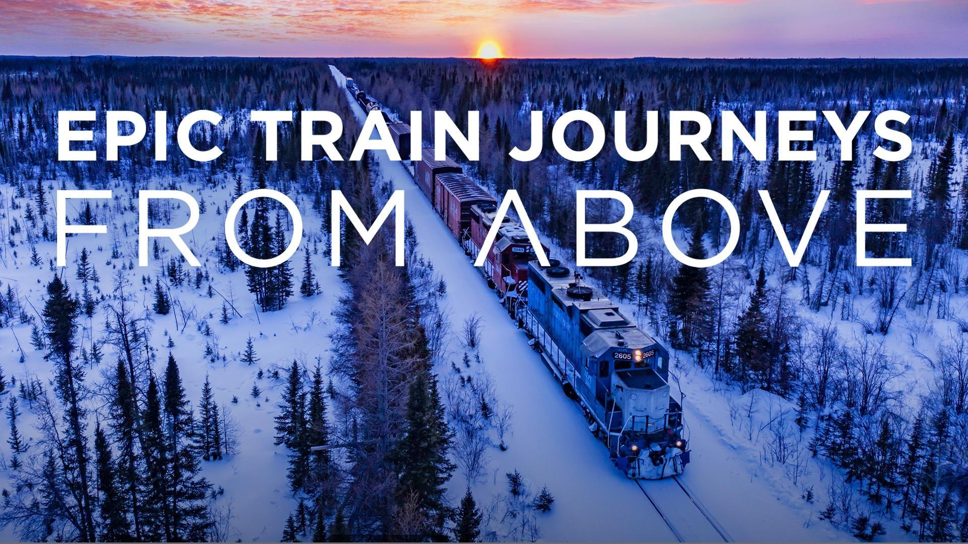 A snow-capped field filled with evergreens with a train running through it. White copy over it that reads: Epic Train Journeys From Above